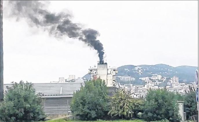 Un bateau sature le ciel de la ville de fumées noires